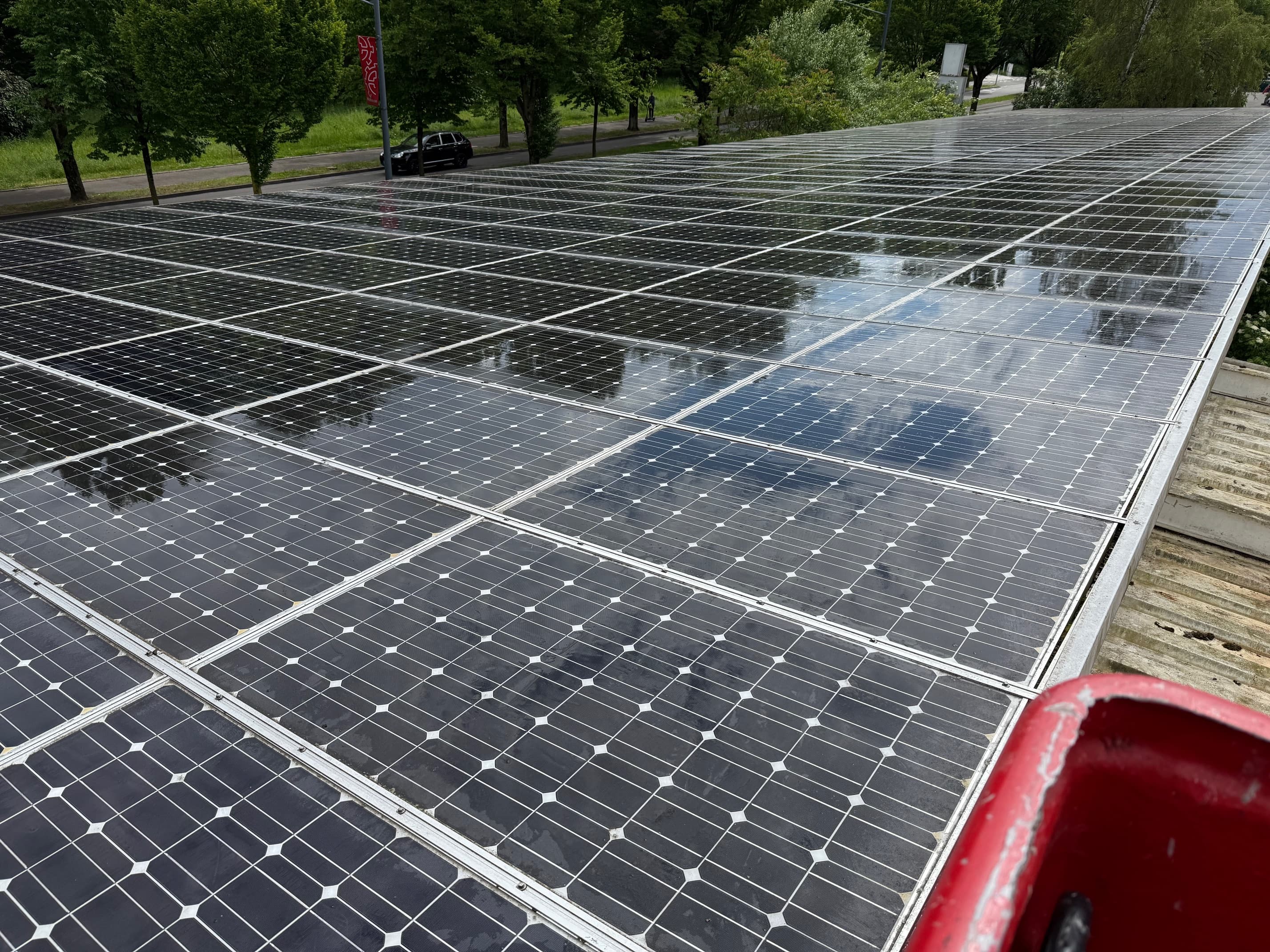 Hangar industriel Grand Est avec panneaux photovoltaïques en cours de nettoyage — partie haute propre et brillante, partie basse encore encrassée